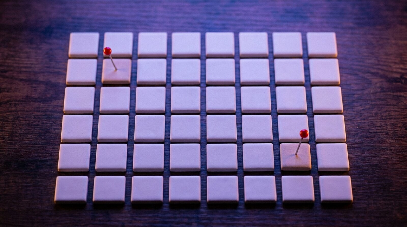 A grid of blank tiles with two marked by a red pin